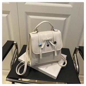 Detail of cream white backpack with bow design, heart pendant and metallic finish