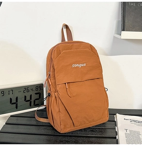 Close-up of caramel nylon backpack with white embroidery and side pocket detail
