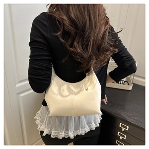 Detail of a creamy white crescent shoulder bag with vertical stitching and zipper closure