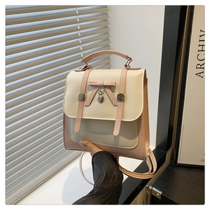 Detail of pink and beige mini backpack with bow and heart charm held by hand