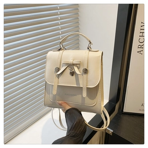 Detail of cream PU leather backpack featuring a bow knot and heart metal charm