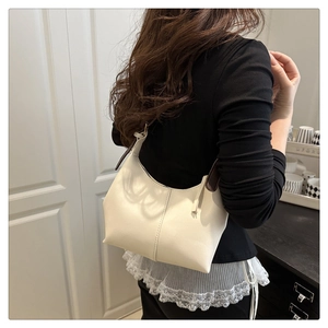 Detail of minimalist cream hobo bag with slim dark brown shoulder strap for women