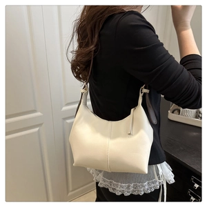 Detail of minimalist cream hobo bag with contrast strap and vertical stitching on leather