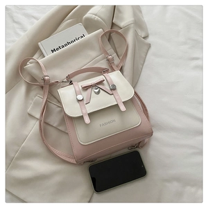Close-up of pink and beige leather backpack featuring a bow and heart pendant detail