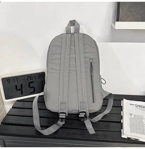 Rear view of grey nylon backpack with adjustable straps and vertical back zipper pocket