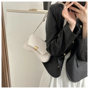 Chic cream white baguette underarm bag with gold buckle on a stylish model in leather jacket
