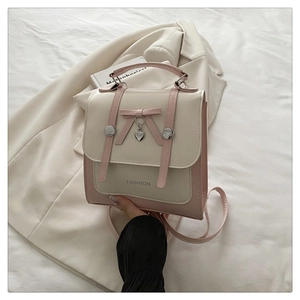 Detail of pink and beige PU leather bag with pink bow and silver heart pendant decoration