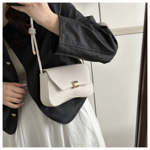 Mirror selfie showing a cream white leather crossbody bag with a wavy base and gold buckle