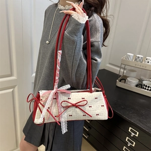 Sac sous le bras crème chic avec nœuds rouges et dentelle porté par un mannequin