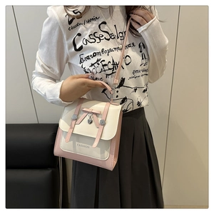 Detail of pink and beige crossbody bag with a cute bow and heart-shaped pendant