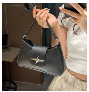 Detail of a black leather underarm bag featuring a metallic silver star buckle closure