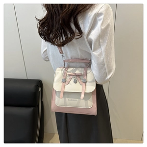 Detail of elegant two-tone backpack with bow, heart pendant and adjustable straps