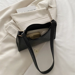 Black croc-effect underarm bag with gold zipper shown on a minimalist cream background