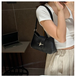 Detailed view of black matte leather underarm bag featuring a silver star metal buckle