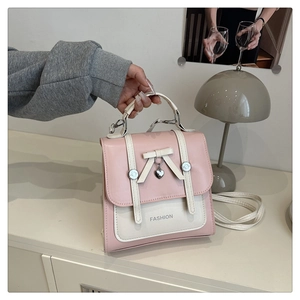 Detailed view of pink and white PU leather handbag with bow and heart metal pendant