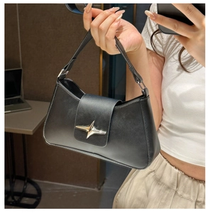 Detail of a black leather handbag featuring a polished silver star metal buckle closure