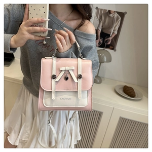 Detail of pink and white PU leather backpack with bow decor and heart pendant charm