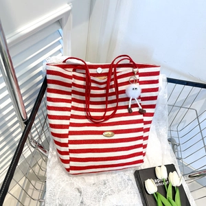 Red and white striped canvas tote bag with red handles and cute plush charm in a cart