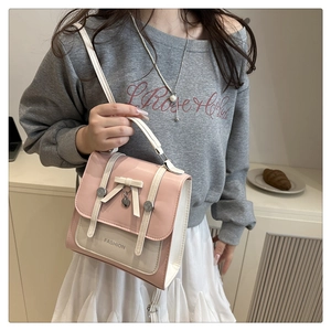 Detail of pink and white crossbody bag with bow decoration and heart charm worn by model