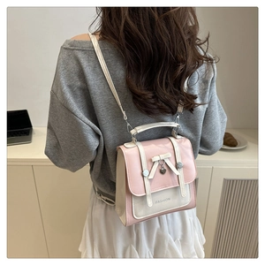 Detail of a pink and cream college-style backpack with a bow and heart charm