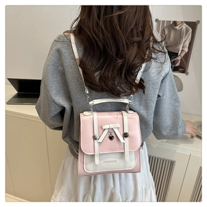 Detail of a pink and cream mini backpack with a white bow and heart pendant on a flap