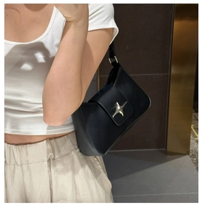 Close-up of black matte faux leather shoulder bag with silver star-shaped metal buckle