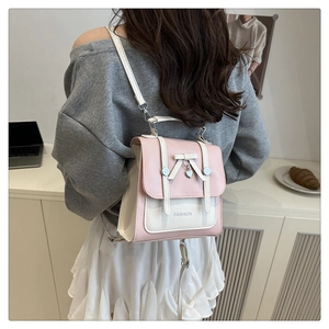 Pink and white patchwork backpack with bow and heart charm worn by a model in a cafe