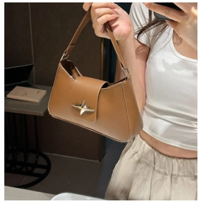 Detail of caramel brown leather underarm bag featuring a silver star metal buckle