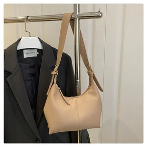 Detail of minimalist beige half-moon hobo bag with adjustable strap and lychee texture