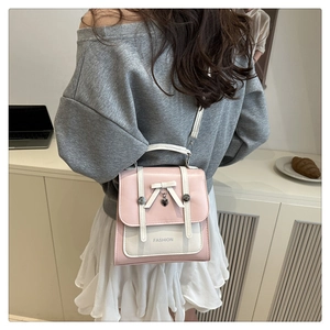 Detail of pink and white faux leather backpack featuring a bow and heart pendant charm
