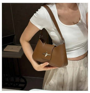 Close-up of caramel brown shoulder bag with a silver star metallic buckle on the flap