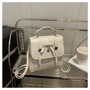 Detail of cream white PU leather backpack with bow accent and heart pendant on a cart