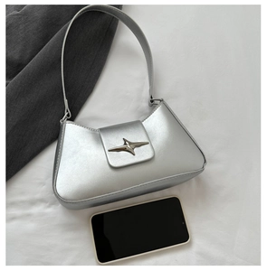 Detail of silver metallic shoulder bag with a star buckle and smartphone for size scale
