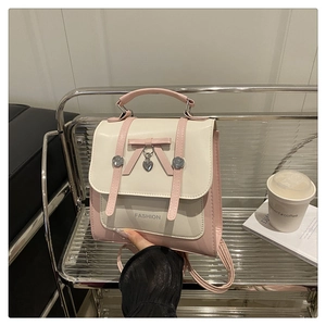 Close-up of pink and cream bow backpack with heart charm and fashion logo text