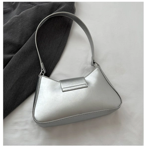 Detailed top view of silver matte underarm bag on white fabric with grey suit background