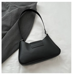 Detailed top view of a black minimalist underarm bag with silver hardware on white linen