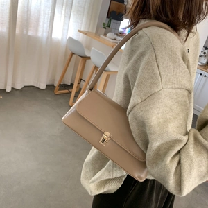 Sac baguette beige minimaliste avec boucle dorée dans un décor intérieur esthétique