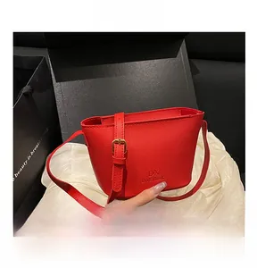 Detail view of red lychee textured leather bucket bag with adjustable gold buckle strap