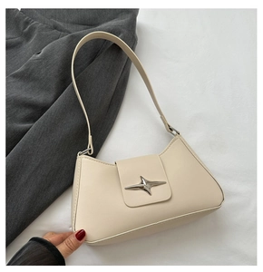 Detailed close-up of cream leather shoulder bag featuring a silver star-shaped metal buckle