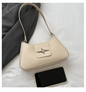 Close-up of beige shoulder bag with silver star buckle and smartphone for scale