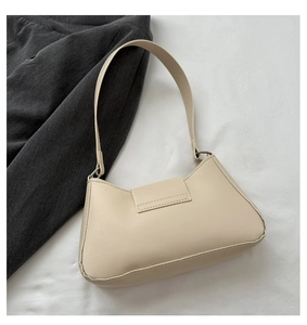 Detail of minimalist beige faux leather shoulder bag with smooth matte texture and silver hardware
