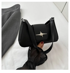 Detail of a black underarm bag featuring a matte finish and silver star-shaped metal buckle