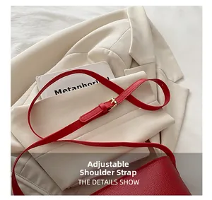 Detail of red lychee grain leather bag showing adjustable shoulder strap with gold buckle