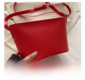 Close-up of red pebble leather bucket bag featuring adjustable strap and logo detail