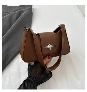 Close-up of brown leather underarm bag with silver star-shaped metal buckle and flap