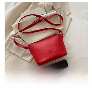 Detail shot of a red lychee leather bucket bag showing its compact size with a smartphone