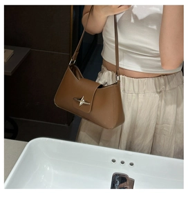 Detail of tan underarm bag with silver star buckle showing strap and mid-size scale