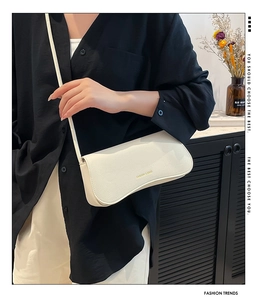 Close-up of cream lychee texture leather shoulder bag with golden hardware and flap
