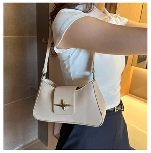 Detail of off-white minimalist underarm bag with silver star buckle worn by a model