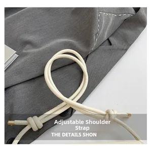 Detail of grey shoulder bag fabric with adjustable white strap and gold hardware